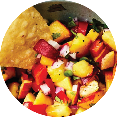 Closeup of fresh peach salsa served with a tortilla chip