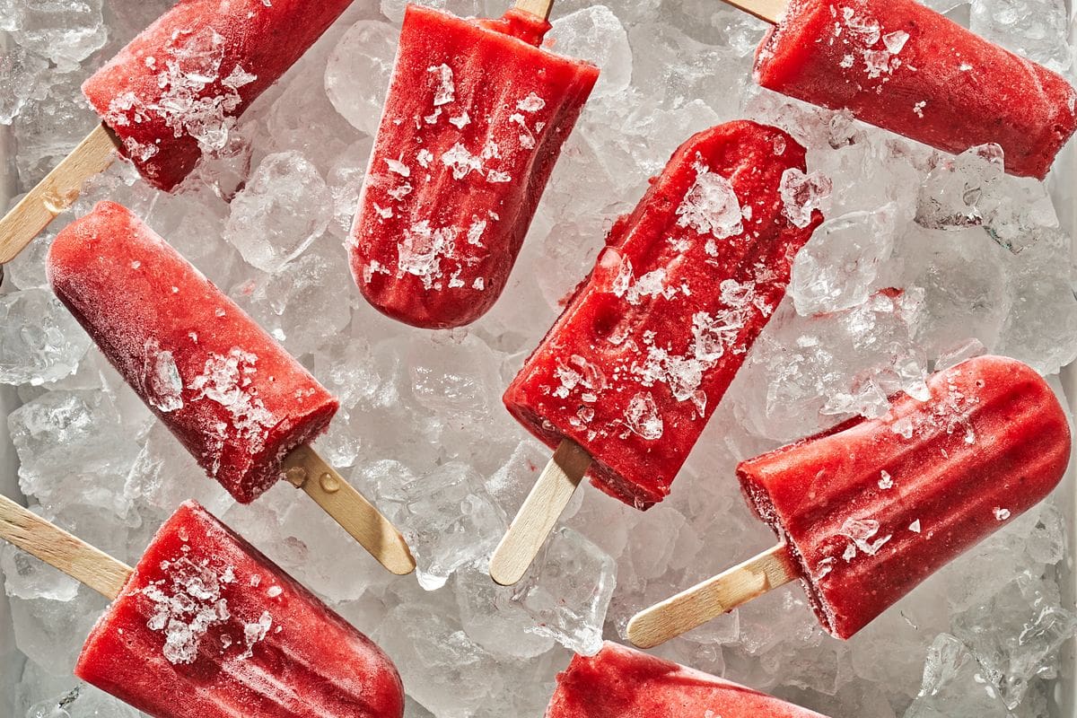 Homemade strawberry popsicles on ice bed